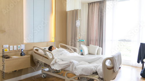 Female patient lying on an inpatient bed in the recovery room treating the illness and being closely monitored by a physician, Modern Adjustable Patient Bed in Hospital, Service point in a hospital
