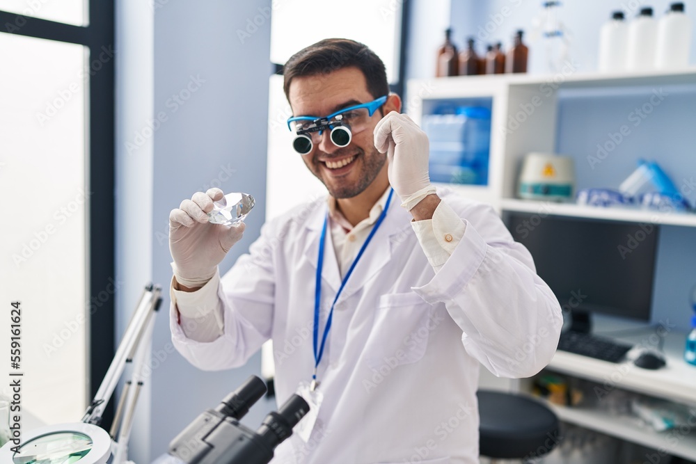 Bild auf Leinwand Young hispanic man scientist looking diamond by magnifying glasses at laboratory