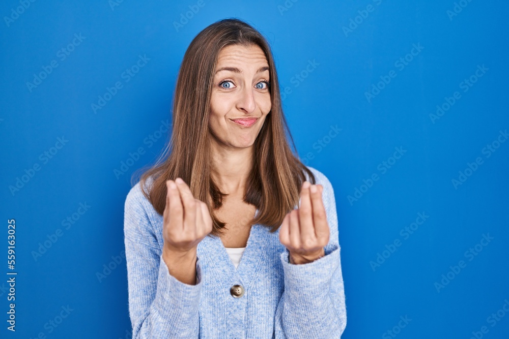 Young woman standing over blue background doing money gesture with hands, asking for salary payment, millionaire business Young woman standing over blue background doing money gesture with hands, asking for salary payment, millionaire business
