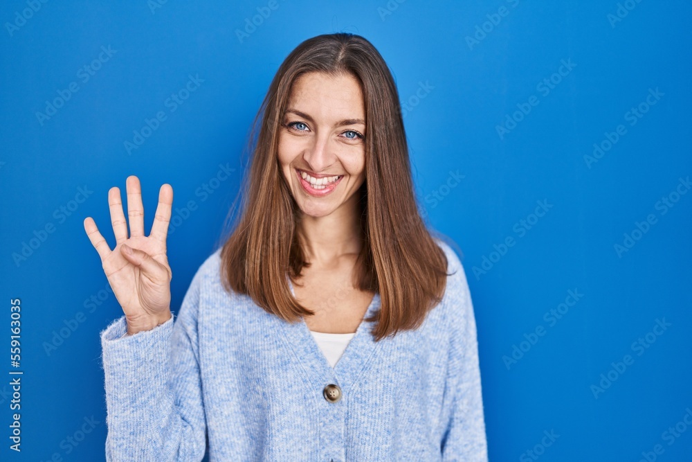 Young woman standing over blue background showing and pointing up with fingers number four while smiling confident and happy. Young woman standing over blue background showing and pointing up with fingers number four while smiling confident and happy.