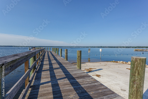 Dock leading out to a large blue lake with a clear blue sky above