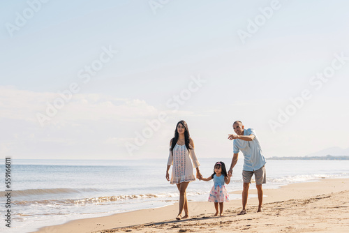 Latin american young family together walking on the beach.