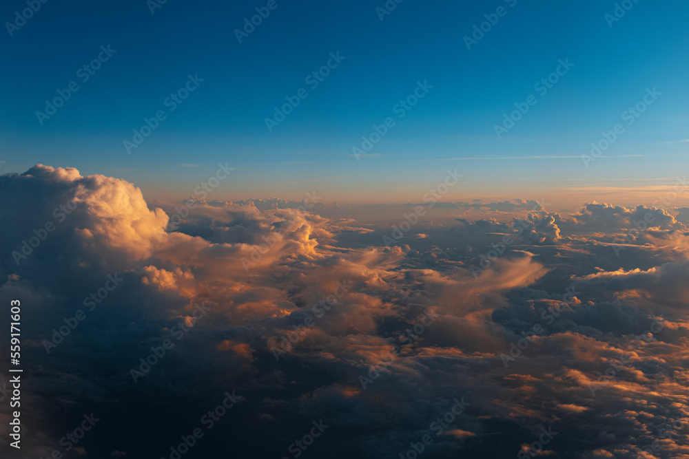 Natural background of sky, sunset above dark clouds, view through window from inside of airplane during the flight.