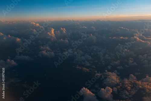 Natural background, sunset above dark clouds, view from inside of airplane during the flight.