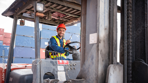 Engineer or foreman working and use talkie with a forklift in at container yard while wearing PPE., Logistics concept inside the shipping, import, and export industries.