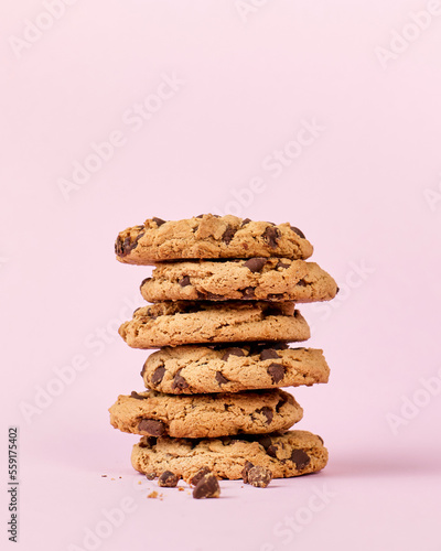 Pile of chocolate cookies on pink background, with copy space
