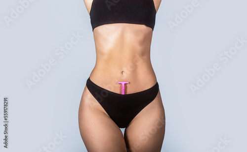 Epilation concepts. Slim woman with perfect body in panties holds razor. Shaving machine in panties. Girl health and intimate hygiene. Beautiful woman's body with smooth soft skin in bikini panties