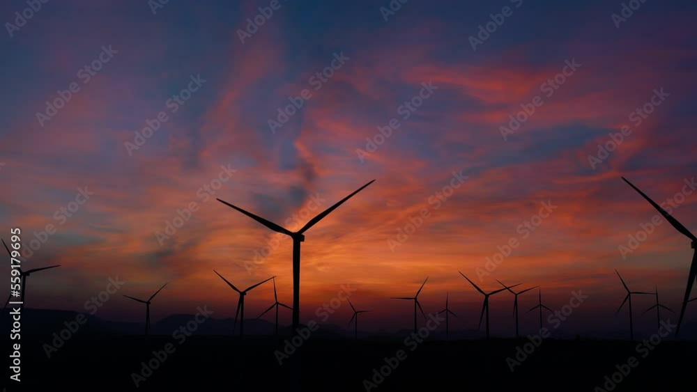 Wind electric generator in the rising sun. Wind generators stand in agricultural fields with Powerful wind turbine farms for pure energy production on the background. 4K Footage.