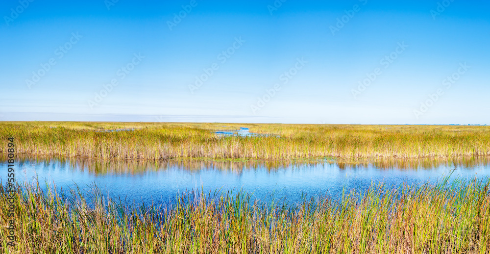 river with dry grassy field with blue sky