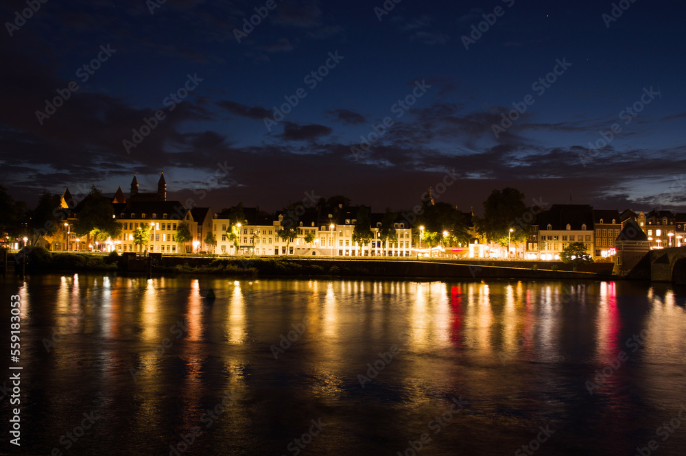 Cityscape of the center of Maastricht in twilight in the Netherlands with in the foreground the river Meuse