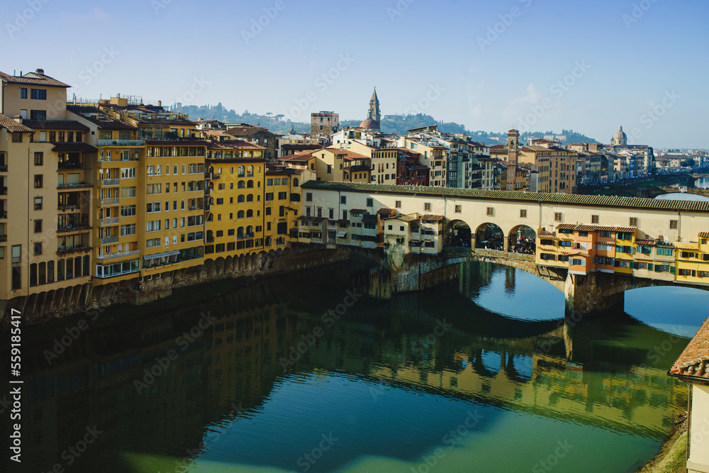 panoramic view of the ponto vecchio bridge and the arno river in florence. reflection in the water of buildings and roofs of houses.