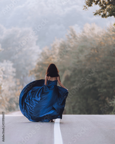 Woman on asphalt wearing blue dress