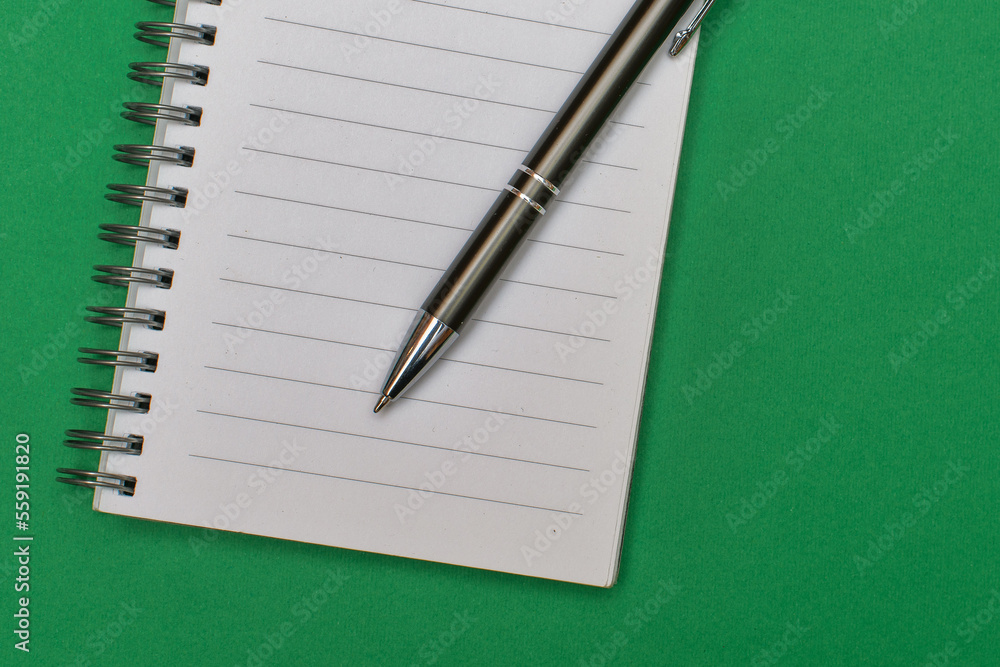 A notebook with a blank page and a pen resting on it A notebook with a blank page and a pen resting on it