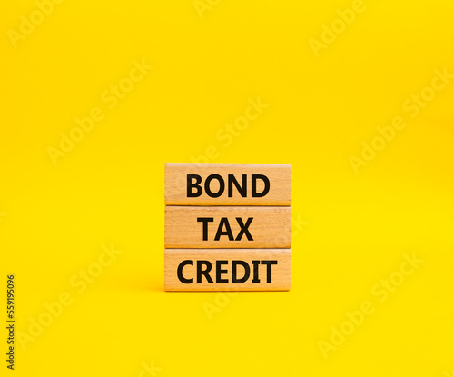 Bond Tax Credit symbol. Concept word Bond Tax Credit on wooden blocks. Beautiful yellow background. Business and Bond Tax Credit concept. Copy space