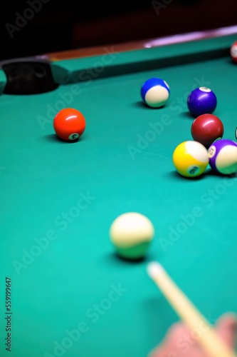 Playing billiards on a green table. A close-up of a billiard ball that the player is aiming at.