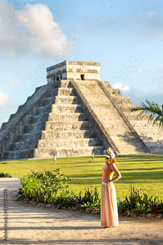 Tableau sur toile A tourist girl in a hat looks at the pyramid of Kukulcan in Chichen Itza