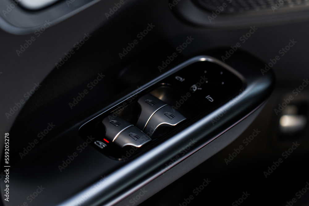 Close up view of button controlling window in modern car interior. Vehicle interior detail. Door handle with windows controls Close up view of button controlling window in modern car interior. Vehicle interior detail. Door handle with windows controls