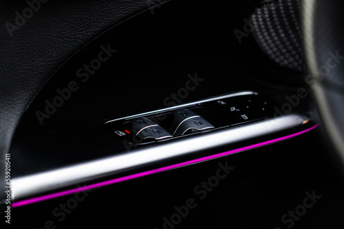 Close up view of button controlling window in modern car interior. Vehicle interior detail. Door handle with windows controls © Roman