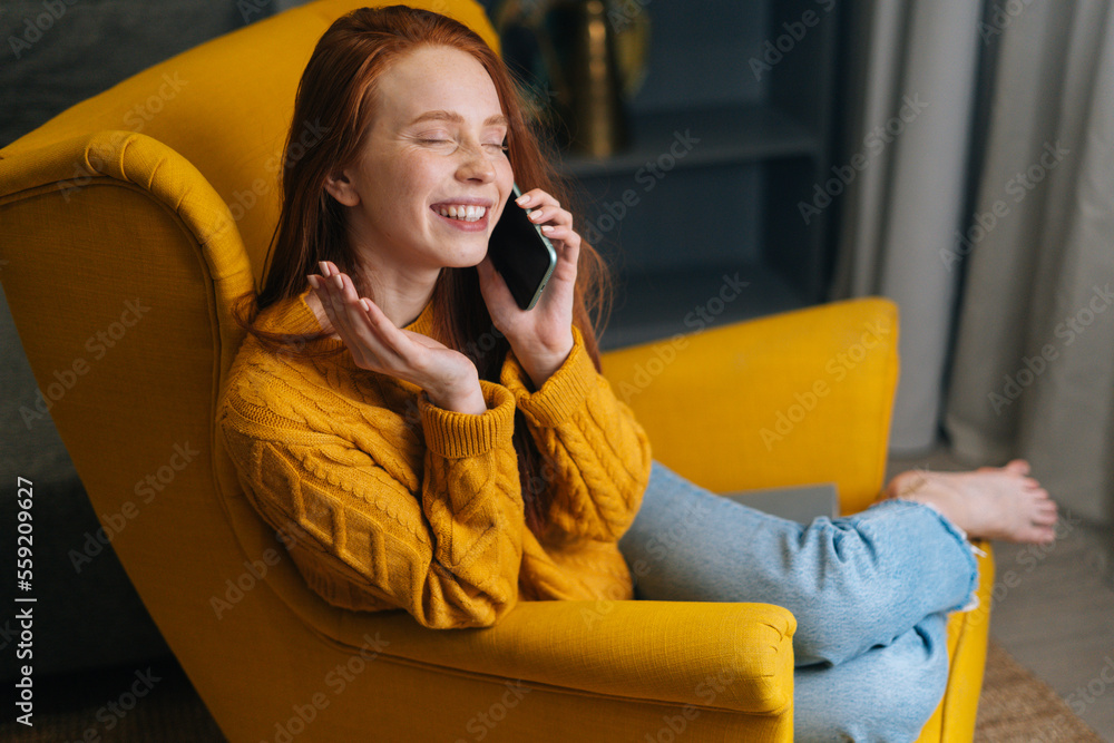 Laughing young woman with closed eyes talking on smartphone