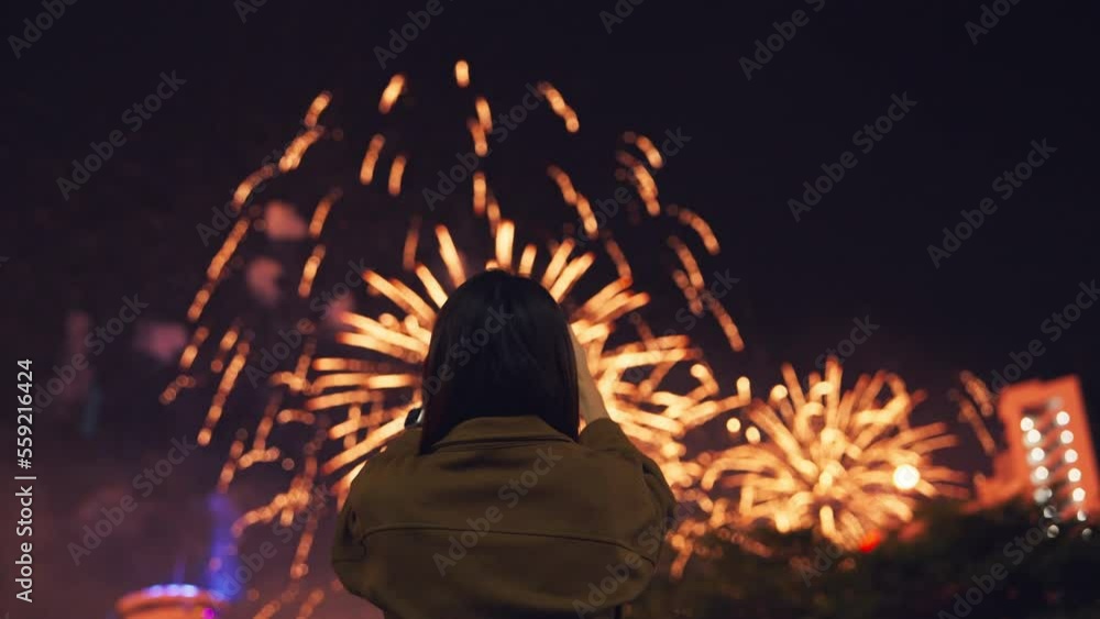 Woman record video incredible new year festivity celebration fireworks on smartphone for upload to social media, Festive holiday Woman record video incredible new year festivity celebration fireworks on smartphone for upload to social media, Festive holiday