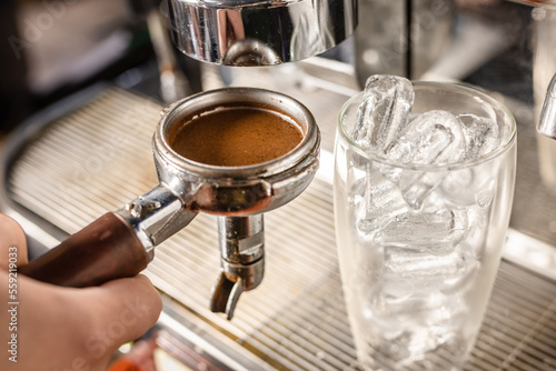 ground coffee with a glass of ice cubes, a barista prepares a coffee drink
