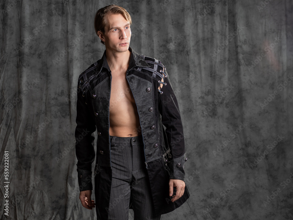 An attractive young man in a fantasy camisole, posing in the studio on a gray fabric background. An attractive young man in a fantasy camisole, posing in the studio on a gray fabric background.