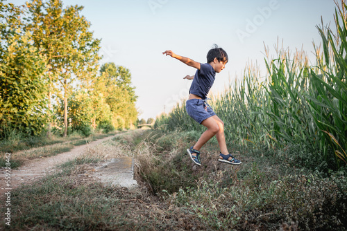 girl wirh short dark hair jumping over pit in corn field