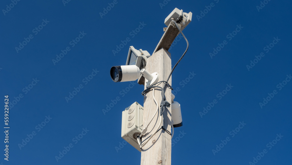 Security cameras and lights on the pole against blue sky Security cameras and lights on the pole against blue sky