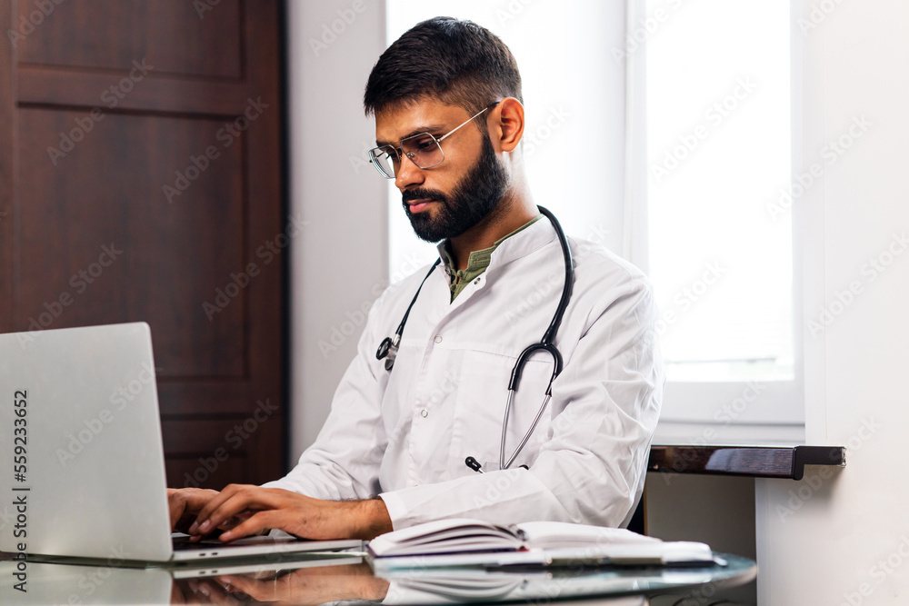 Portrait of male indian doctor wearing white coat in clinic office Portrait of male indian doctor wearing white coat in clinic office