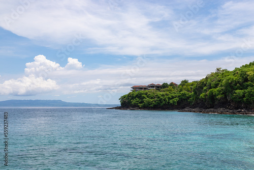 Bias Tugel beach at the south of Bali island. Many tourists swimming in blue ocean water. White sand and rock shore.