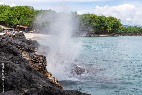 Beautiful nature fountain near Bias Tugel beach at the south of Bali island. White sand and rock shore.