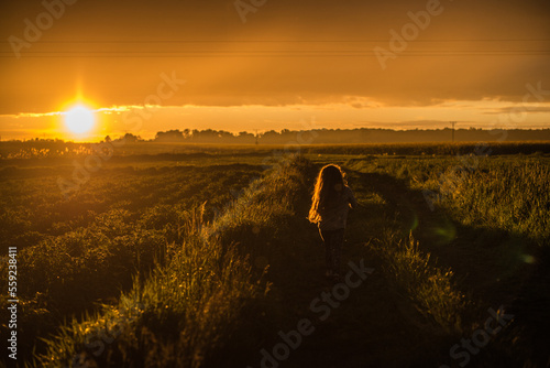 little girl running on sunset background photo