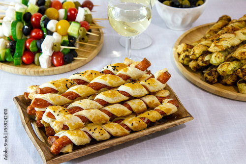 Przekąski na przyjęcie sylwestrowe lub karnawał: kabanosy we francuskim cieście, paluszki z ciasta francuskiego i pesto, szaszłyki z pomidorami, oliwkami i serem serwowane z białym winem photo