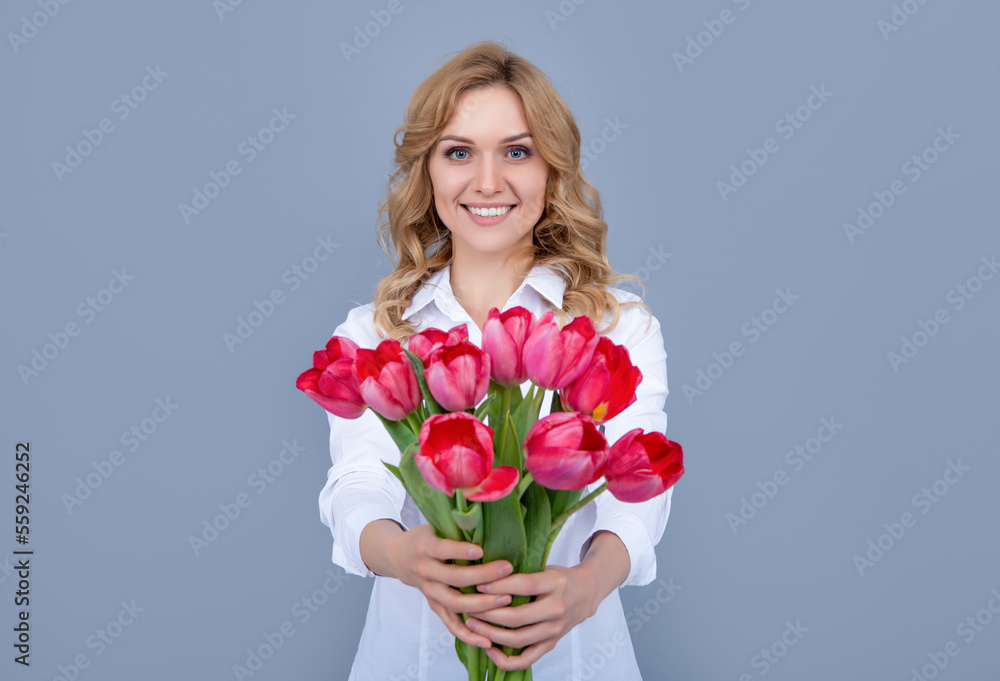 blond woman smile with spring tulip flowers on grey background blond woman smile with spring tulip flowers on grey background