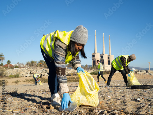 Young African American volunteer woman collects garbage in nature. Earth Day concept