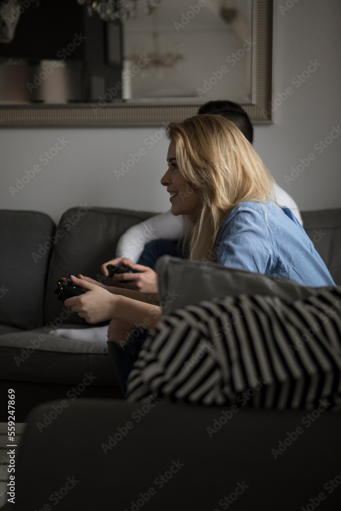 Happy couple playing video game on sofa at home Happy couple playing video game on sofa at home
