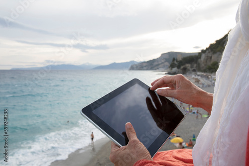 Detail of woman using digital tablet above sea photo