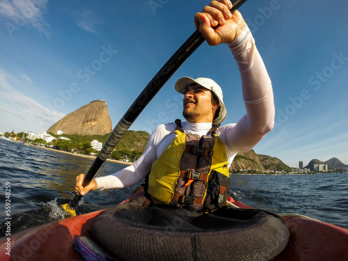 Man kayaking in Baia de Guanabara with Pao de Acucar mountain in background, Rio de Janeiro, Brazil photo