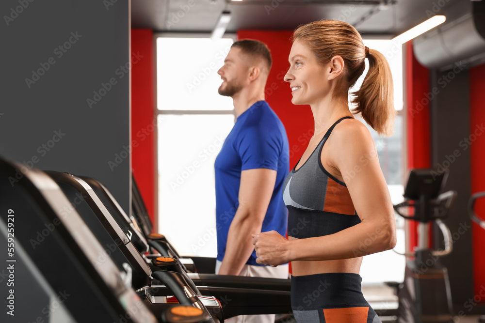 Beautiful couple training on treadmills in gym Beautiful couple training on treadmills in gym