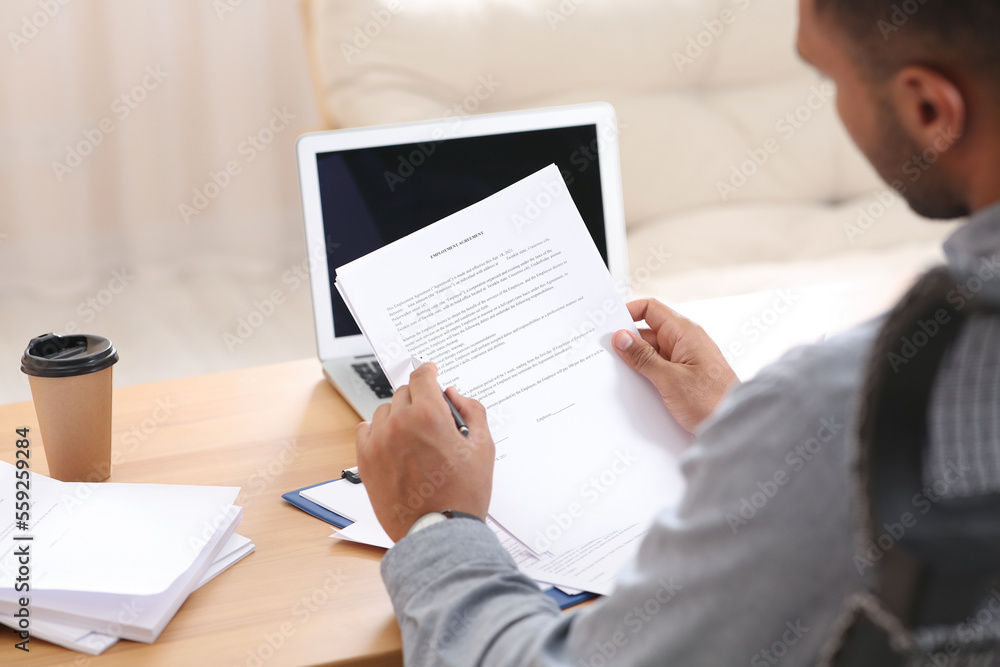 Man working with documents at wooden table in office, back view Man working with documents at wooden table in office, back view