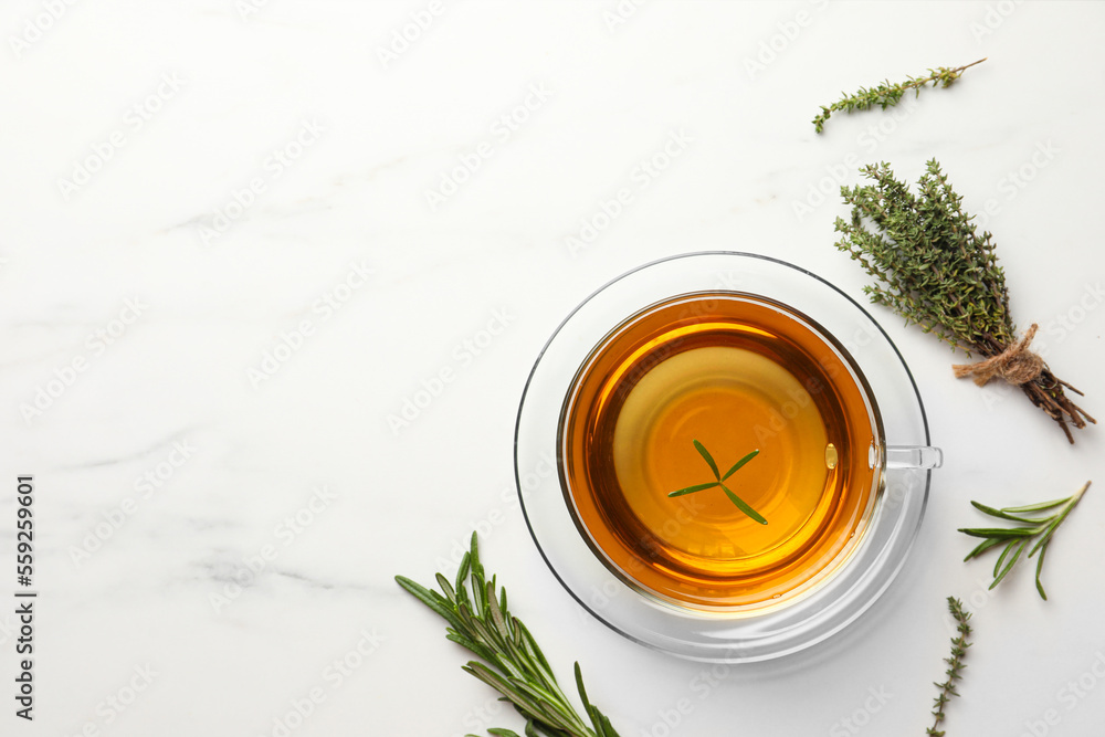 Cup of aromatic herbal tea with thyme and rosemary on white marble table, flat lay. Space for text - obrazy, fototapety, plakaty 