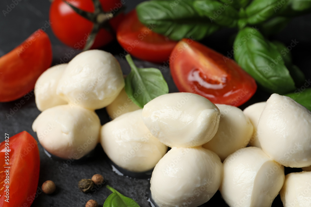 Delicious mozzarella balls, tomatoes and basil leaves on black table, closeup Delicious mozzarella balls, tomatoes and basil leaves on black table, closeup