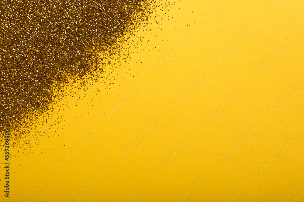 Shiny golden glitter on yellow background, top view. Space for text