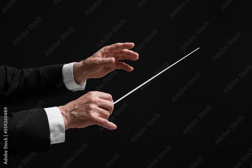 Professional conductor with baton on black background, closeup - obrazy, fototapety, plakaty 