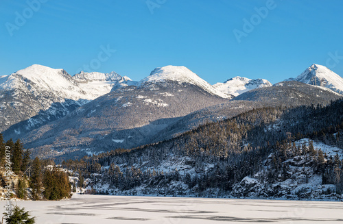 Whistler BC, Canada - December 12th, 2022: A snow covered mountain range and frozen lake near Whistler BC, Canada.