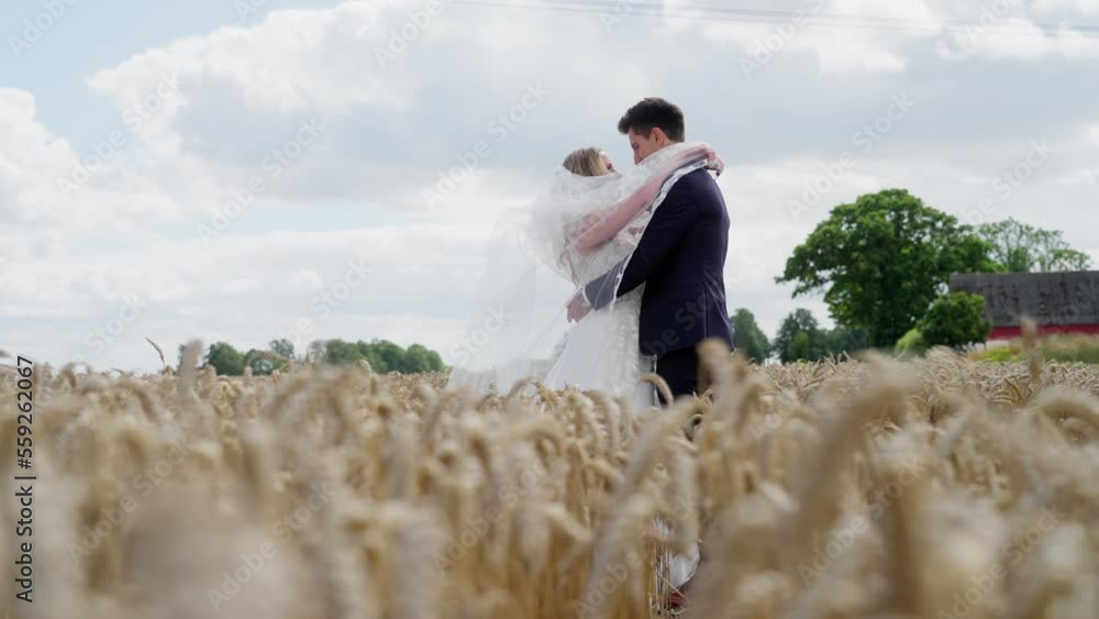 Stunning bride wrapping her arms and vail around her new husband in beautiful slow motion scene Stunning bride wrapping her arms and vail around her new husband in beautiful slow motion scene