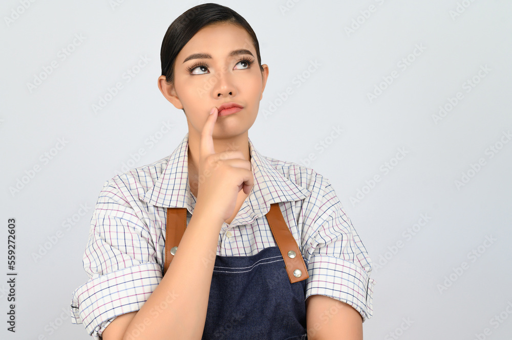 Portrait of thoughtful young asian woman in waitress costume ingenious poseture Portrait of thoughtful young asian woman in waitress costume ingenious poseture