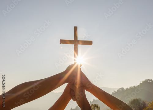 Obraz na płótnie Silhouette family hands praying and holding Christian cross for worshipping God on mountain at sunrise background