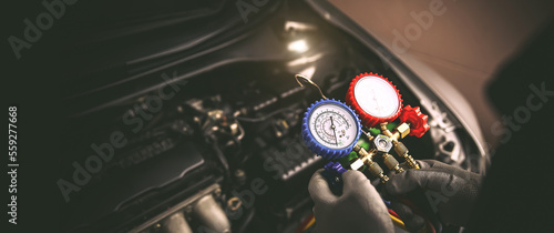 Car care maintenance and servicing, Hand technician auto mechanic using measuring manifold gauge check refrigerant and filling car air conditioner to fix repairing heat conditioning system.