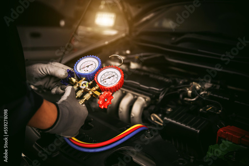 Car care maintenance and servicing, Hand technician auto mechanic using measuring manifold gauge check refrigerant and filling car air conditioner to fix repairing heat conditioning system.